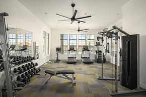 Mesa apartment for rent - A spacious gym with a variety of equipment and a ceiling fan.