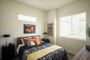 Mesa apartment for rent - A bedroom with a bed, a lamp, a wall hanging and a window.