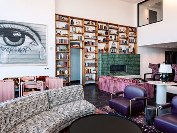 Denver apartment for rent - A living room with a large eye painting on the wall and a bookshelf filled with books.