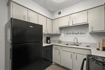 Hendersonville apartment for rent - A black refrigerator in a kitchen with a sign that says Live Laugh Love.