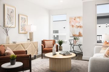 Boulder apartment for rent - A living room with a brown sofa, a white armchair, a wooden coffee table, and a painting on the wall.