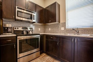 Tucson apartment for rent - A kitchen with dark wood cabinets and stainless steel appliances.