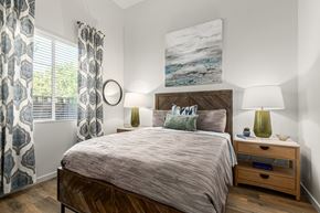 Scottsdale apartment for rent - A bedroom with a large bed, a nightstand with a lamp, and a painting on the wall.