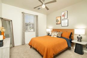 Tucson apartment for rent - A bedroom with a bed, a ceiling fan, and a window with curtains.