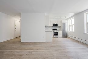 East York apartment for rent - an empty living room with white walls and a kitchen at 111 Cosburn, Ontario