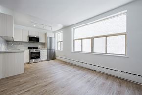East York apartment for rent - an empty kitchen with white cabinets and a large window at 111 Cosburn, East York, M4J 2L1