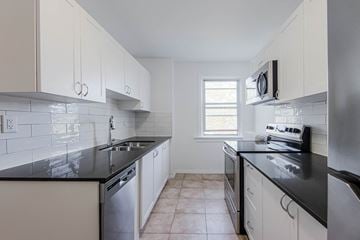 Toronto apartment for rent - A kitchen with white cabinets and black countertops.
