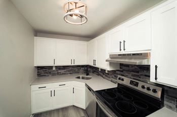 A kitchen with white cabinets and a black stove