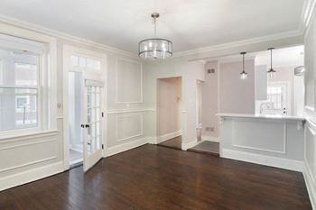 An empty living room and kitchen with white walls and wood floors