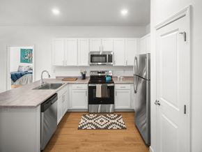 South Burlington apartment for rent - A kitchen with white cabinets and a black and white rug on the floor.