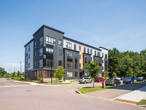 South Burlington apartment for rent - A modern multi-story apartment building with cars parked in front.