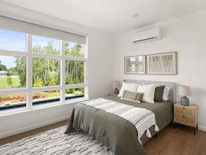 South Burlington apartment for rent - A bedroom with a large bed and a view of trees through the window.