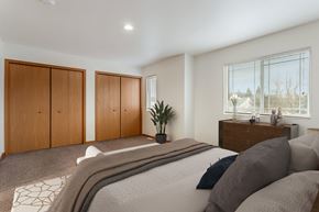Portage apartment for rent - A bedroom with a large bed and a window with blinds.