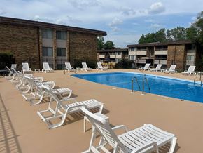 Kalamazoo apartment for rent - A row of white chairs are lined up on a tan pool deck.