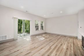 Holland apartment for rent - A spacious room with wooden flooring and sliding glass doors leading to a wooded area.