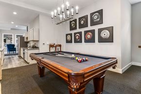 Westerville apartment for rent - A pool table with a brown leather cover and a white cue ball is in the center of the room.