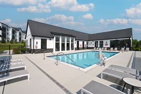 Ann Arbor apartment for rent - A large outdoor swimming pool with sun loungers and a building in the background.