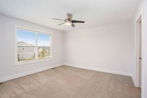 Hudsonville apartment for rent - A room with a ceiling fan and a window showing a view of houses.