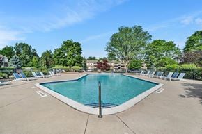 Bloomfield Hills apartment for rent - A large swimming pool surrounded by lounge chairs and trees.