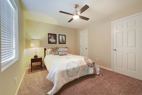 Little Rock apartment for rent - A bedroom with a bed, a ceiling fan, and two pictures on the wall.