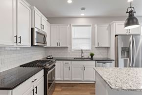 Plymouth apartment for rent - A kitchen with white cabinets and a black stove top.