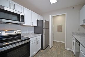 New Hudson apartment for rent - A kitchen with white cabinets and a black stove top oven.