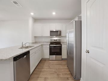 Byhalia apartment for rent - A kitchen with white cabinets and a stainless steel refrigerator.