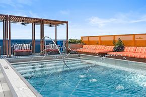 Cleveland apartment for rent - A pool with a waterfall and a bench with orange cushions.
