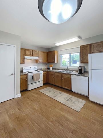 East Lansing apartment for rent - A kitchen with wooden cabinets and white appliances.