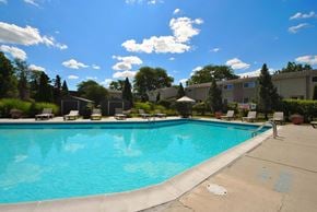 East Lansing apartment for rent - A large swimming pool with a blue tinted water and a white fence around it.