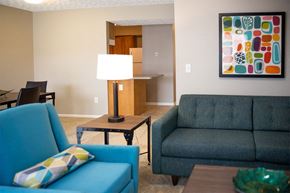 Canal Winchester apartment for rent - A blue chair with a pillow sits in a living room with a lamp and a couch.