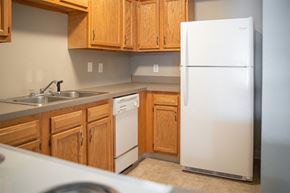 Canal Winchester apartment for rent - A white refrigerator stands in a kitchen with wooden cabinets.