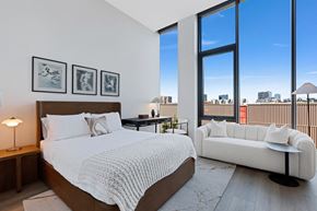 Chicago apartment for rent - a bedroom with a bed and a couch and tall windows