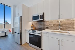 Chicago apartment for rent - a kitchen with white cabinets and a sink and a refrigerator