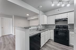Bentonville apartment for rent - A kitchen with black appliances and white cabinets.