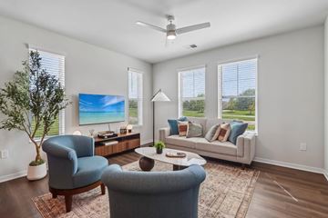 Cottage Grove apartment for rent - A living room with a blue chair, a grey sofa, a wooden coffee table, and a painting on the wall.