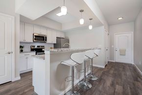Grove City apartment for rent - A kitchen with white cabinets and a bar area with stools.