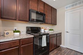 Columbus apartment for rent - A kitchen with brown cabinets and a black stove top oven.