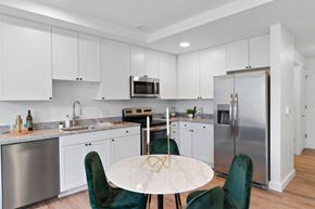 Detroit apartment for rent - a kitchen with white cabinets and stainless steel appliances and a round table