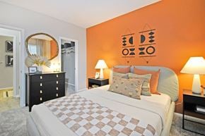 Holland apartment for rent - a bedroom with an orange accent wall and a large bed