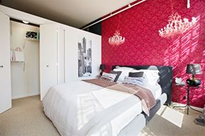 Chicago apartment for rent - a bedroom with a red wall and a white bed