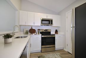 Howell apartment for rent - A kitchen with white cabinets and a black refrigerator.