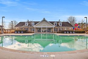 Chattanooga apartment for rent - A large swimming pool in front of a building with a playground in the background.