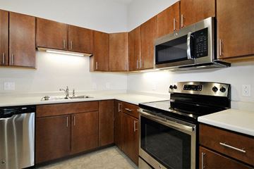 Lansing apartment for rent - A kitchen with brown cabinets and a black stove top oven.