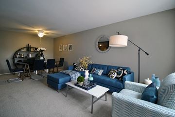 Lansing apartment for rent - A living room with a blue couch and a white coffee table.