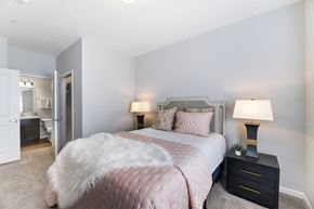 Columbus apartment for rent - A bedroom with a bed covered in a pink comforter and a white fur throw.