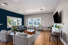 Rockford apartment for rent - A living room with a black couch, grey armchairs, a wooden coffee table, and a flat-screen TV mounted on the wall.