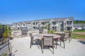 Rockford apartment for rent - A patio with a table and chairs is in front of apartment buildings.