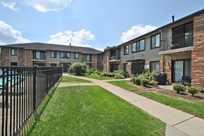 Livonia apartment for rent - A sunny day at a residential complex with a pool and green lawns.