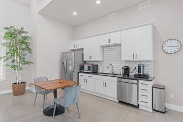 Victoria apartment for rent - A kitchen with a table and chairs in the foreground and a refrigerator, microwave, and oven in the background.
